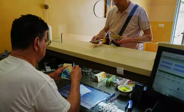 A currency exchange employee counts Israeli Shekels at a bureau in the West Bank city of Bethlehem, Tuesday, July 7, 2026. (AP Photo/Mahmoud Illean)