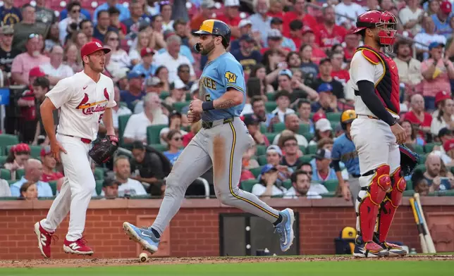Milwaukee Brewers' Garrett Mitchell, center, scores between St. Louis Cardinals starting pitcher Andre Pallante, left, and catcher Iván Herrera during the third inning of a baseball game Thursday, July 9, 2026, in St. Louis. (AP Photo/Jeff Roberson)
