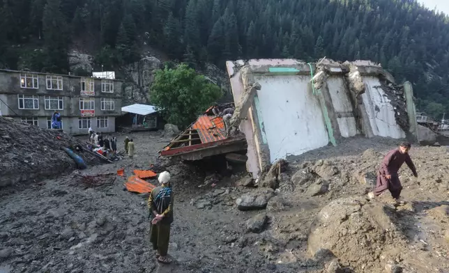 Residents and rescue workers inspect buildings damaged by heavy flooding in the eastern province of Nuristan, Afghanistan, Tuesday, July 21, 2026. (AP Photo/Wahidullah Kakar)