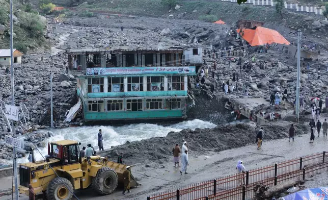 Residents and rescue workers inspect buildings damaged by heavy flooding in the eastern province of Nuristan, Afghanistan, Tuesday, July 21, 2026. (AP Photo/Wahidullah Kakar)