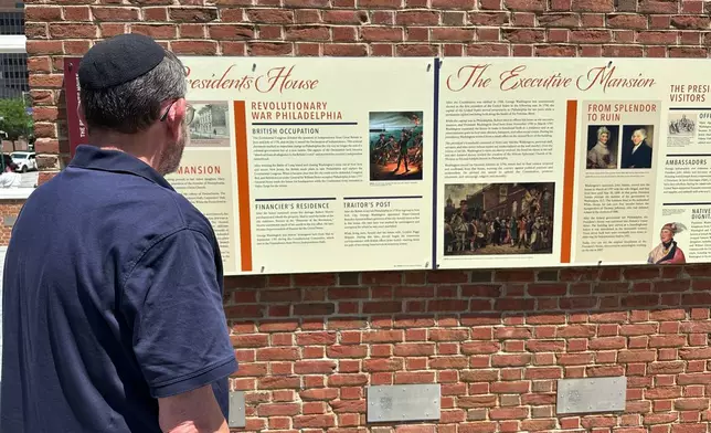 Visitors view the reinstalled educational panels about slavery at the site of President George Washington's home in Philadelphia, Wednesday, July 15, 2026. (AP Photo/Tassanee Vejpongsa)