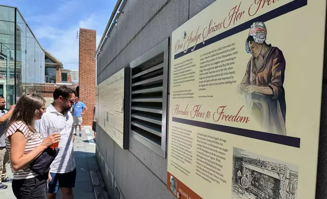 Visitors view the reinstalled educational panels about slavery at the site of President George Washington's home in Philadelphia, Wednesday, July 15, 2026. (AP Photo/Tassanee Vejpongsa)