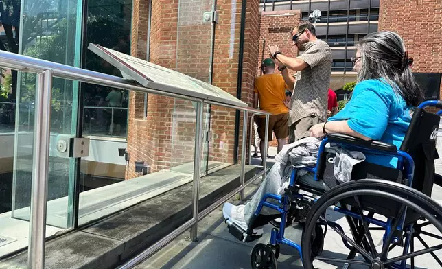 Visitors view the reinstalled educational panels about slavery at the site of President George Washington's home in Philadelphia, Wednesday, July 15, 2026. (AP Photo/Tassanee Vejpongsa)