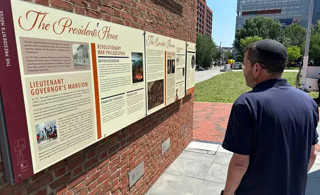 Visitors view the reinstalled educational panels about slavery at the site of President George Washington's home in Philadelphia, Wednesday, July 15, 2026. (AP Photo/Tassanee Vejpongsa)