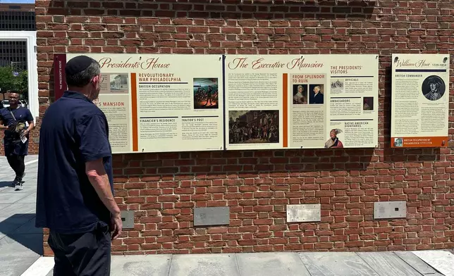 Visitors view the reinstalled educational panels about slavery at the site of President George Washington's home in Philadelphia, Wednesday, July 15, 2026. (AP Photo/Tassanee Vejpongsa)