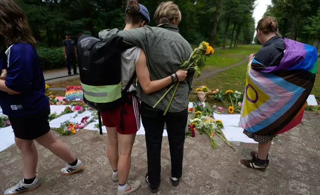 Two people hug at the memorial site commemorating the victims near the scene where a car rammed into a crowd at the Pride March in Berlin, Germany, Sunday, July 26, 2026. (AP Photo/Markus Schreiber)