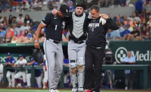 Chicago White Sox catcher Kyle Teel, center, his helped off the field by manager Will Venable (1) and trainer Brett Walker, right, during the second inning of a baseball game against the Texas Rangers, Monday, July 20, 2026, in Arlington, Texas. (AP Photo/LM Otero)