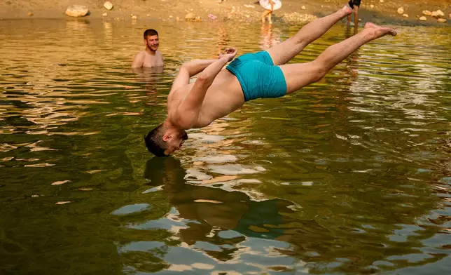A youngster jumps in a river as the National Weather forecaster issued an extreme heat code red warning for most parts of the country, outside 1 Decembrie, Romania, Tuesday, June 30, 2026. (AP Photo/ Andreea Alexandru)