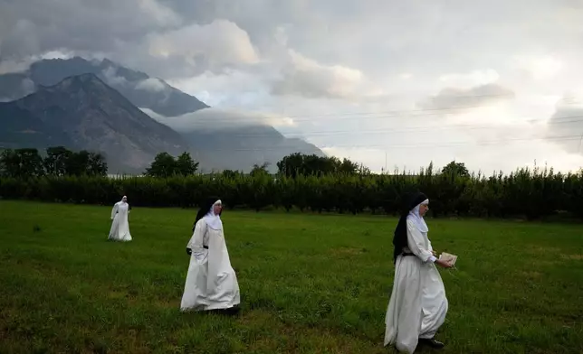 Nuns make their way to a tent set up outside the Society of St. Pius X seminary to attend a consecration ceremony for four new bishops in Econe, Switzerland, Wednesday, July 1, 2026. (AP Photo/Baz Ratner)