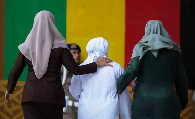 Shariah law officials escort a woman convicted of violating Islamic law by kissing a man, both unmarried, during a TikTok livestream after her public caning, in Banda Aceh, Indonesia, Thursday, July 2, 2026. (AP Photo/Reza Saifullah)