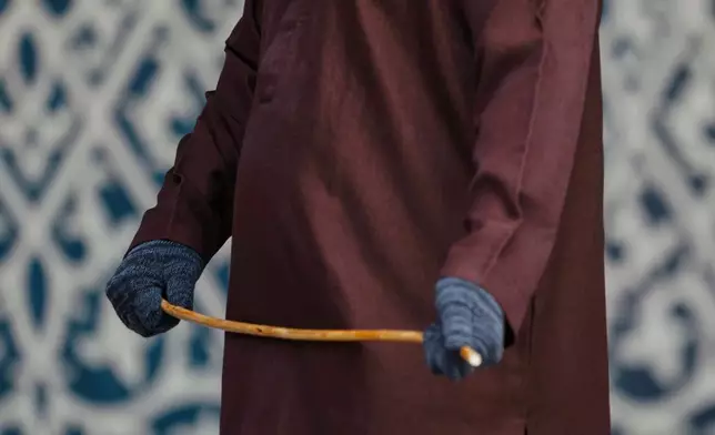 A shariah law official holds a rattan cane before the public caning of a young couple after an Islamic Shariah court convicted them of violating Islamic law by kissing during a TikTok livestream, in Banda Aceh, Indonesia, Thursday, July 2, 2026. (AP Photo/Reza Saifullah)