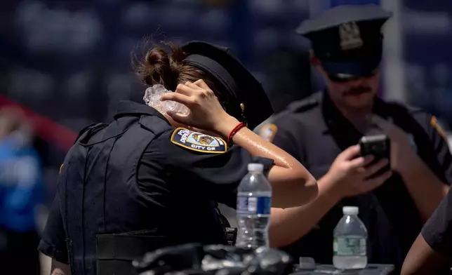 FILE - A police officer holds ice to their neck to try and stay cool following the 2026 Nathan's Famous Fourth of July hot dog eating contest at Coney Island in the Brooklyn borough of New York, July 4, 2026. (AP Photo/Anna Connors, File)