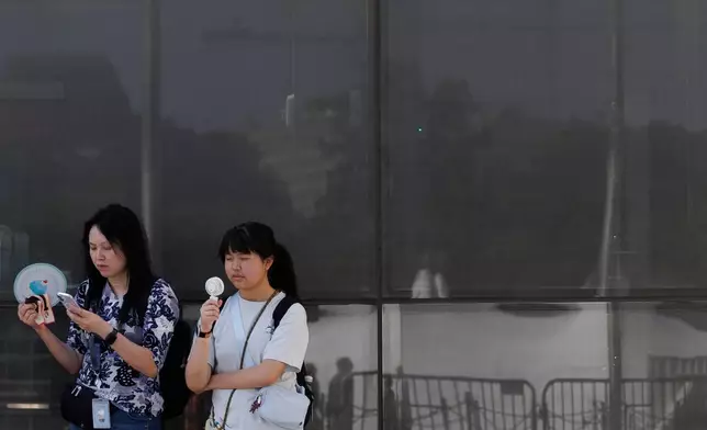 FILE - Visitors use fans as as they wait to enter the Washington Monument, July 1, 2026, in Washington. (AP Photo/Tom Brenner, File)