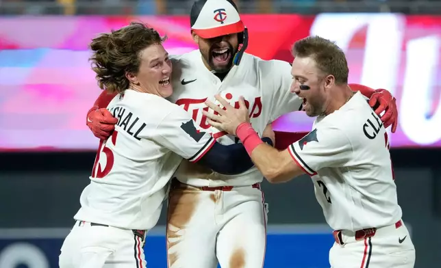Minnesota Twins' Royce Lewis, center, celebrates with Luke Keaschall, left, and Kody Clemens after hitting an RBI triple walk-off scoring Victor Caratini and Brooks Lee in the ninth inning of a baseball game against the Kansas City Royals, Tuesday, July 28, 2026, in Minneapolis. (AP Photo/Joseph Scheller)