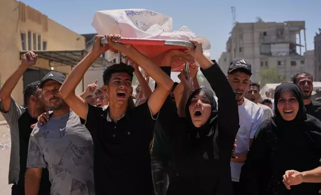 Warda Abu Shaar, center right, carries the body of her 10-year-old son, Motaz Abu Shaar, who was killed by Israeli fire, during his funeral outside Nasser Hospital in Khan Younis, southern Gaza Strip, Tuesday, July 14, 2026. (AP Photo/Abdel Kareem Hana)