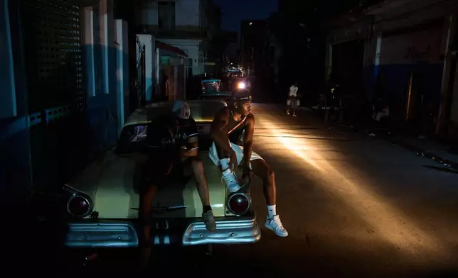 Men sit on the trunk of a car during a blackout in Havana, Cuba, Tuesday, July 14, 2026. (AP Photo/Ramon Espinosa)