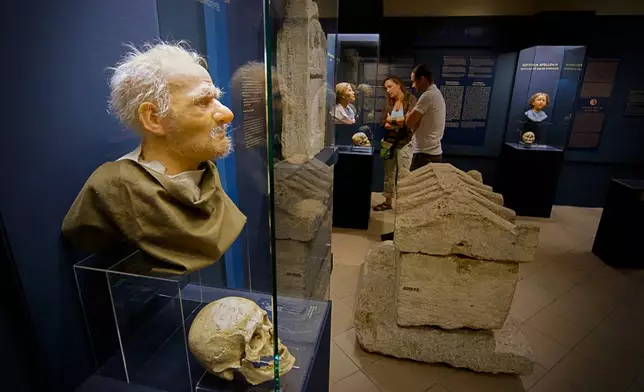 Visitors look at Roman-era skulls and their facial reconstructions in the Aquincum Museum's exhibition titled "Once we were like you" which showcases characters and the fictional life stories of those who once lived in the bustling Roman settlement of Aquincum, in Budapest, Hungary, Tuesday, July 7, 2026. (AP Photo/Bela Szandelszky)