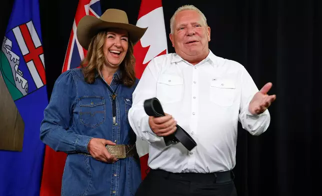 Alberta Premier Danielle Smith, left, and Ontario Premier Doug Ford swap belt buckles after announcing the Northern Shield pipeline proposal in Calgary, Canada, Monday, July 6, 2026. (Jeff McIntosh/The Canadian Press via AP)