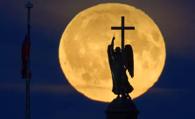 The full moon rises behind a statue of an angel fixed atop the Alexander Column at the Palace Square in St. Petersburg, Russia, Wednesday, July 29, 2026. (AP Photo/Dmitri Lovetsky)