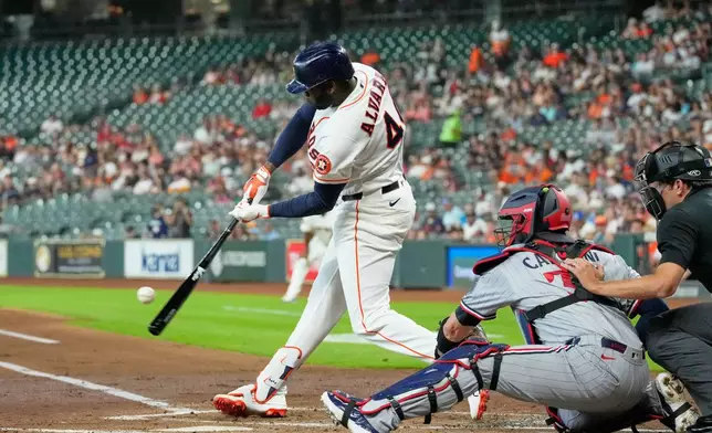Houston Astros' Yordan Alvarez (44) hits a single as Minnesota Twins catcher Victor Caratini reaches for the pitch during the first inning of a baseball game Tuesday, June 30, 2026, in Houston. (AP Photo/David J. Phillip)