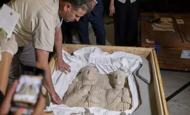 A museum employee opens a crate containing Palmyrene funerary reliefs that once adorned the walls of tombs and date to the second and third centuries A.D. after Syrian authorities unveiled antiquities returned from France at the National Museum in Damascus, Syria, Wednesday, July 8, 2026.(AP Photo/Ghaith Alsayed) ADDITION: Adds identification of the artifact as Palmyrene funerary reliefs.