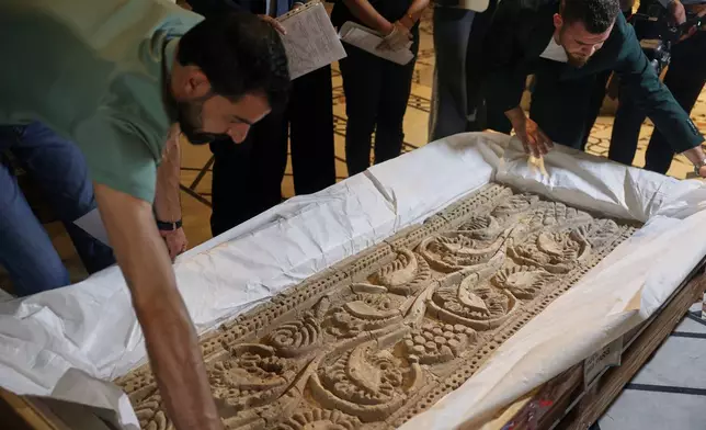 Museum employees unpack a carved stone panel after Syrian authorities unveiled antiquities returned from France at the National Museum in Damascus, Syria, Wednesday, July 8, 2026.(AP Photo/Ghaith Alsayed)