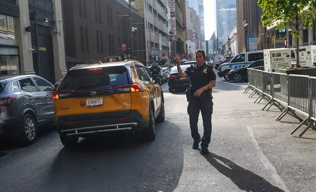 An NYPD officer waves through cars outside of Madison Square Garden ahead of a reported wedding between singer Taylor Swift and National Football League player Travis Kelce on Thursday, July 2, 2026, in New York. (AP Photo/Ryan Murphy)