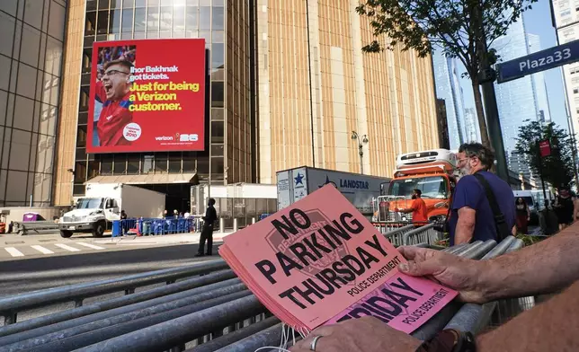 A worker holds "No Parking" signs prior to posting as trucks fill the loading dock outside New York's Madison Square Garden, Wednesday, July 1, 2026. (AP Photo/Richard Drew)
