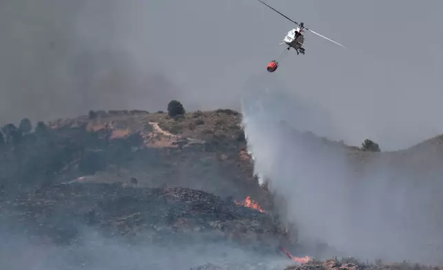 A helicopter drops water while fighting a wildfire near Los Gallardos, Almeria, Spain, Friday, July 10, 2026. (AP Photo/Gregorio Marrero)