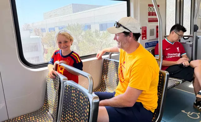 Matthew Smith and his son Whitacre, 5, ride the Metro after a World Cup match between Spain and Austria on Thursday, July 2, 2026, in Los Angeles. (AP Photo/Jaimie Ding)