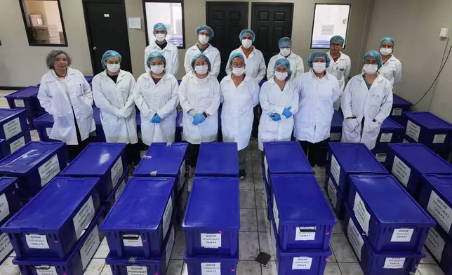 Archivists pose for a group photo with boxes containing testimonies from victims of the internal armed conflict between 1960 and 1996, who sought reparations for the abuses they suffered, in Guatemala City, Wednesday, July 22, 2026. (AP Photo/Moises Castillo)
