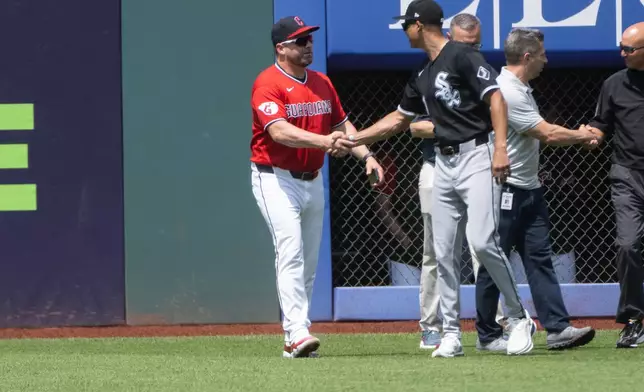 Cleveland Guardians manager Stephen Vogt, left, shakes hands with Chicago White Sox manager Will Venable, front right, after inspecting field repairs before a baseball game, Sunday, July 5, 2026, in Cleveland. (AP Photo/Phil Long)