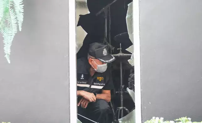 A forensic police officer inspects the site of a fire in Bangkok, Thailand, Monday, July 13, 2026. (AP Photo/Sakchai Lalit)