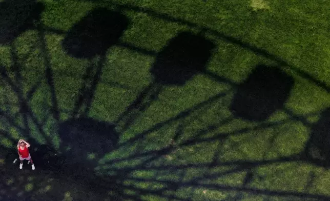 Robbin Sorrell stands in the shadow of a ferris wheel at the Great American State Fair on the National Mall, Thursday, July 2, 2026, in Washington. (AP Photo/Tom Brenner)