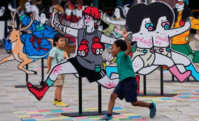 Children play near an art display at an outdoor shopping mall in Beijing, Tuesday, June 30, 2026. (AP Photo/Andy Wong)