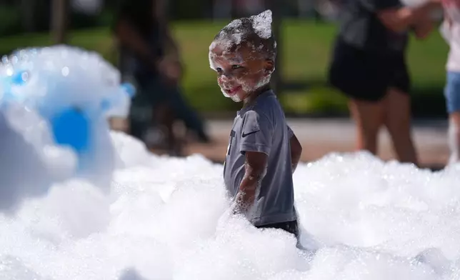 A child takes in the scene of bubbles at Hall Park in the Dallas suburb of Frisco, Texas, Sunday, June 28, 2026. (AP Photo/LM Otero)