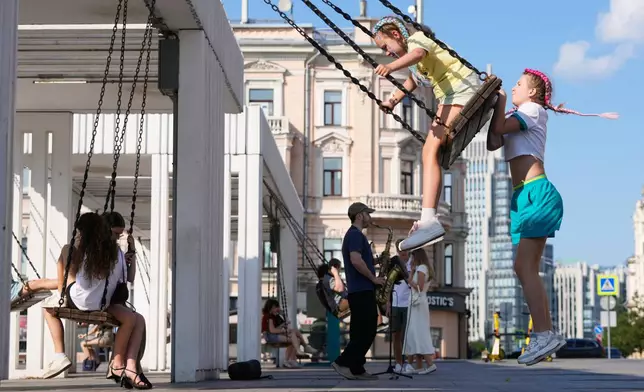 People ride on swings on a hot summer day in Moscow, Wednesday, July 1, 2026. (AP Photo/Pavel Bednyakov)