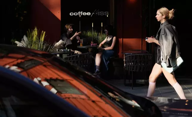 People sit at an outdoor table of a cafe on a hot summer day in Moscow, Wednesday, July 1, 2026. (AP Photo/Pavel Bednyakov)
