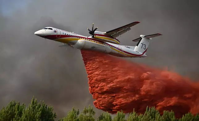 FILE - A plane releases fire retardant as it flies over a forest near Blagon, during wildfires in southwestern France, July 29, 2026. (AP Photo/Emma Da Silva, File)