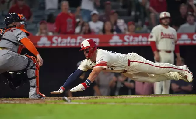 Los Angeles Angels' Mike Trout (27) scores on Jorge Soler's double as Houston Astros' Christian Vazquez (2) awaits the throw during the fifth inning of a baseball game Tuesday, July 28, 2026, in Anaheim, Calif. (AP Photo/Scott Strazzante)