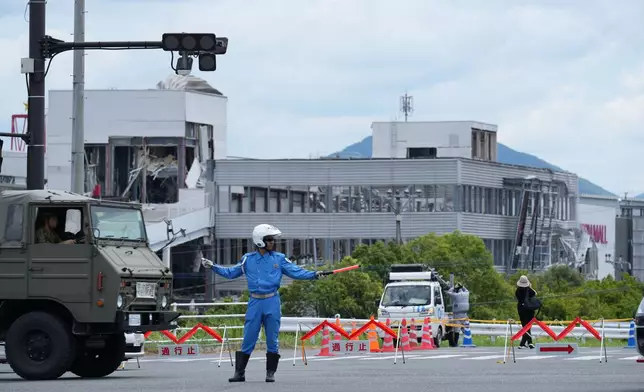 A police officer controls the traffic near AEON Mall, which was destroyed by an explosion following an earthquake, in Kashima, Kumamoto Prefecture, southern Japan, Wednesday, July 29, 2026. (AP Photo/Hiro Komae)