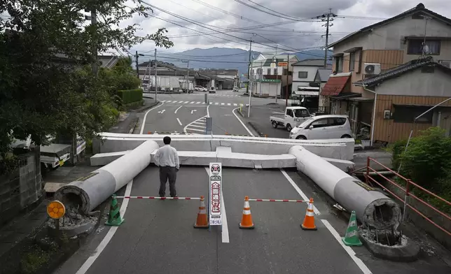 People stand by the fallen torii gate near a shrine, a day after an earthquake in Yatsushiro, Kumamoto prefecture, Wednesday, July 29, 2026.(Yu Nakajima/Kyodo News via AP)