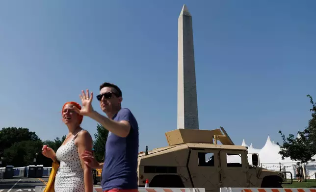 People cross 15th Street Northwest as a National Guard Humvee blocks the roadway, Wednesday, July 1, 2026, in Washington. (AP Photo/Tom Brenner)