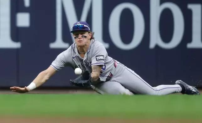 Colorado Rockies' Cole Carrigg dives and catches a ball off the bat of the Milwaukee Brewers' Brice Turang during the fifth inning of a baseball game Saturday, July 25, 2026, in Milwaukee. (AP Photo/Jeffrey Phelps)
