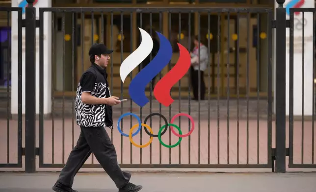 A man walks past a fence with Olympic Rings in front of the Russian National Olympic Committee building in Moscow, on Tuesday, July 7, 2026. (AP Photo/Pavel Bednyakov)