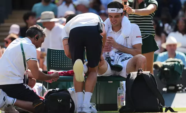 Taylor Fritz of the United States receives medical attention during a changeover in his quarter-final men's singles match against Alexander Zverev of Germany, at the Wimbledon Tennis Championships in London, Wednesday, July 8, 2026. (AP Photo/Kin Cheung)
