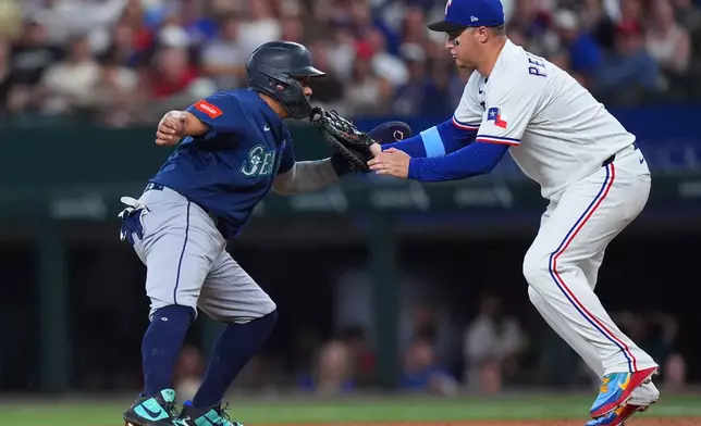 Seattle Mariners' Josh Naylor, left, is caught stealing second base on a rundown against Texas Rangers first baseman Joc Pederson during the second inning of a baseball game, Saturday, July 25, 2026, in Arlington, Texas. (AP Photo/LM Otero)