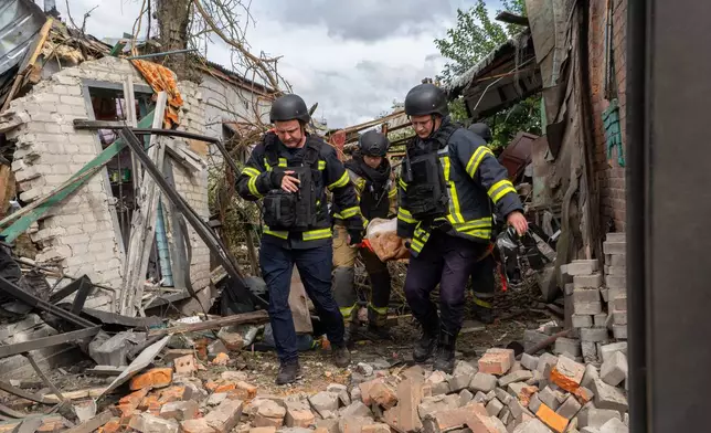 Rescuers carry a body that they removed from under the rubble of an private house following a drone attack from Russia, in Kharkiv, Ukraine, Sunday, July 26, 2026. (AP Photo/Andrii Marienko)