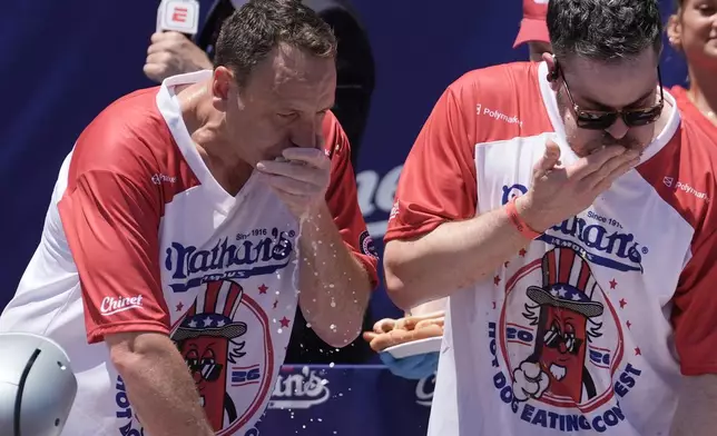Joey Chestnut and other competitive eaters consume hot dogs during the 2026 Nathan's Famous Fourth of July hot dog eating contest at Coney Island in the Brooklyn borough of New York, Saturday, July 4, 2026. (AP Photo/Anna Connors)
