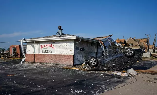 An upside down car sits in front of a damaged bakery after a tornado struck Monday, July 27, 2026, in Menasha, Wis. (AP Photo/Kayla Wolf)